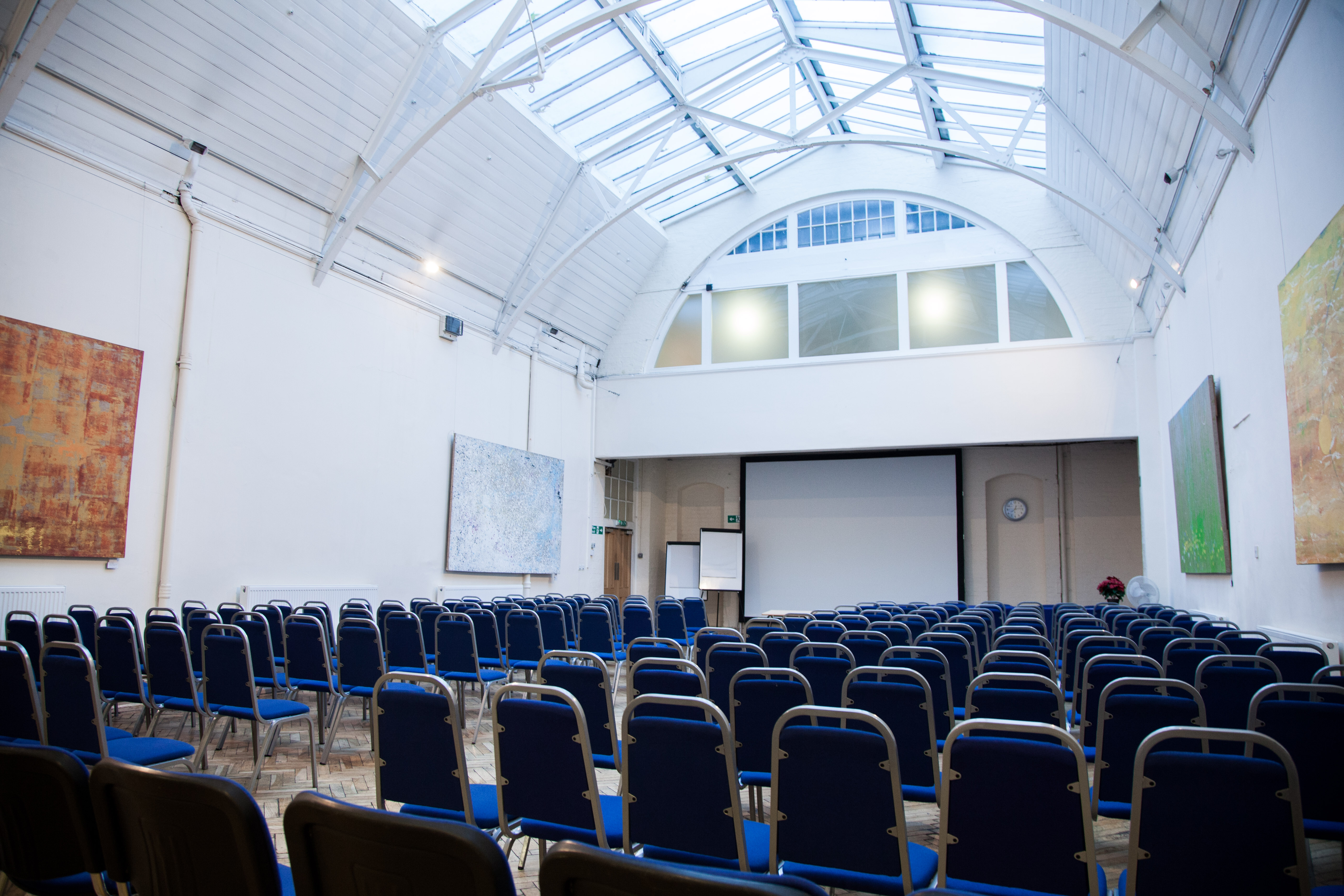 Spacious event venue with blue chairs, ideal for conferences and workshops.