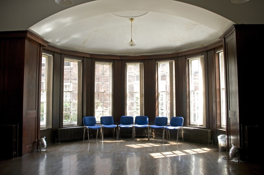 Dickens Library meeting room with blue chairs, ideal for workshops and discussions.