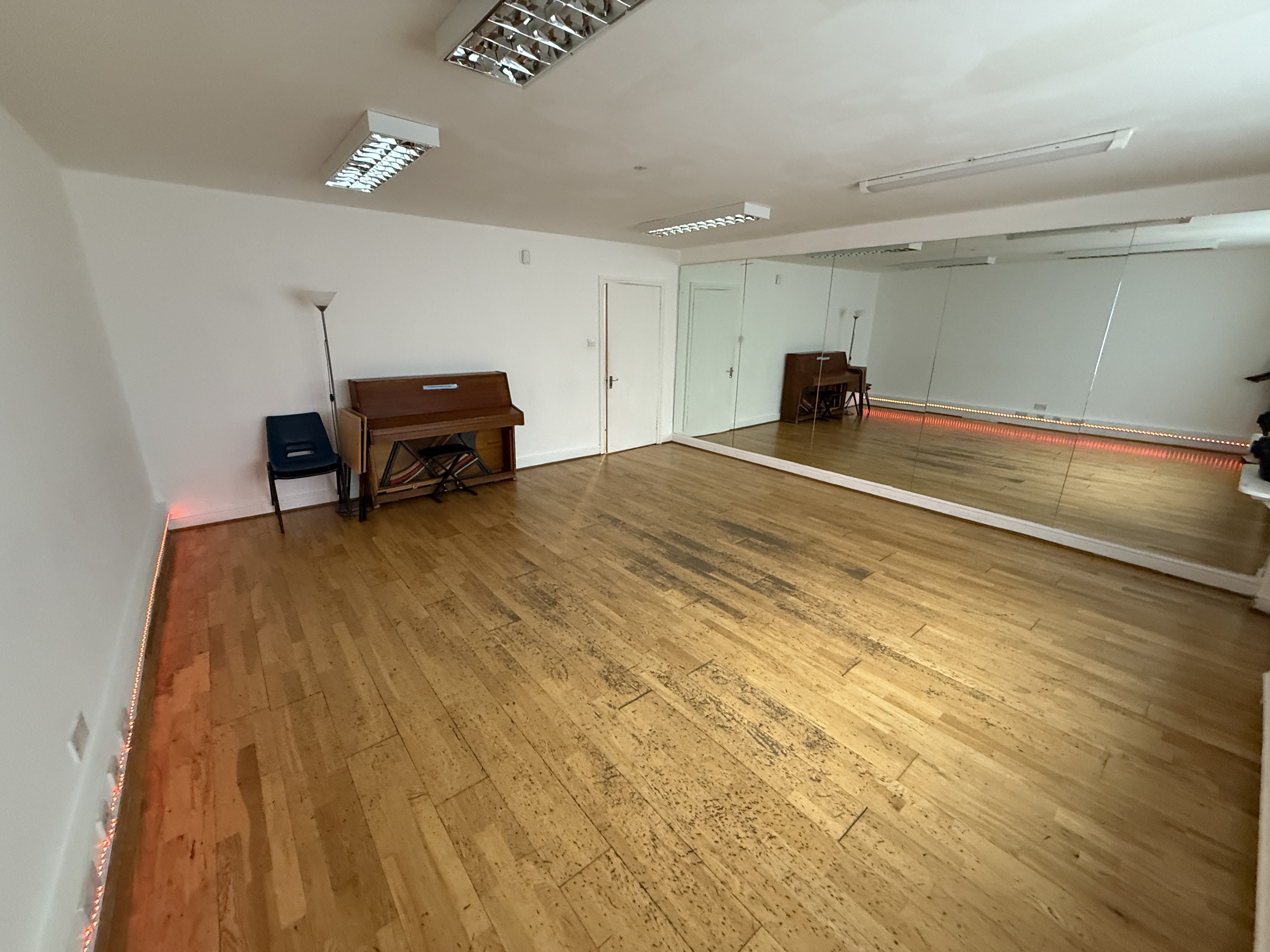 Versatile event space with polished floors and piano, perfect for workshops and gatherings.