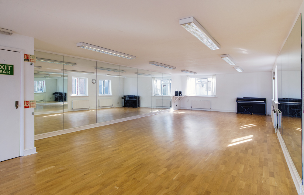 Versatile event space with polished wooden floor and mirrors for workshops or dance classes.