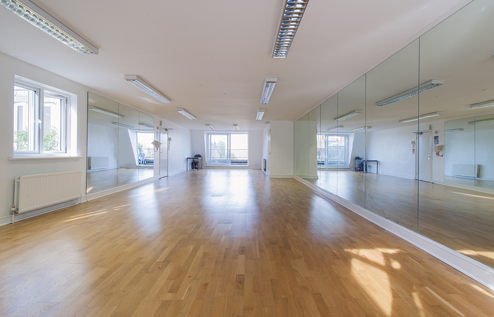 Spacious, well-lit studio with wooden floors for workshops and fitness classes.