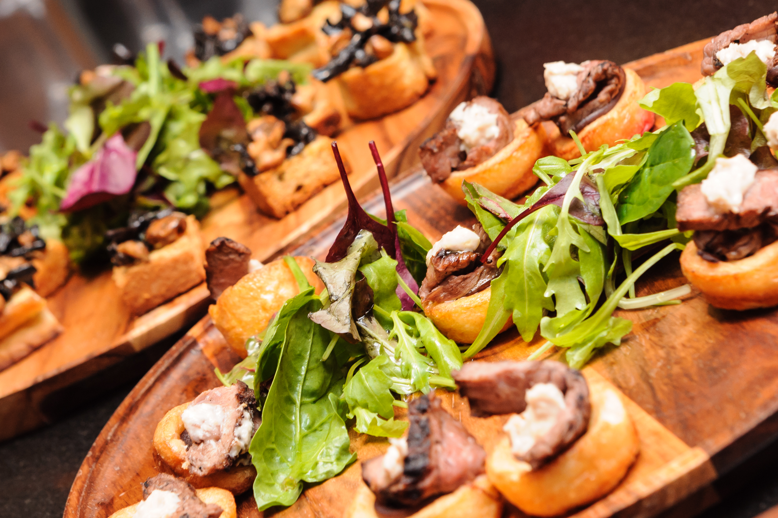 Gourmet hors d'oeuvres on wooden platters at upscale networking event