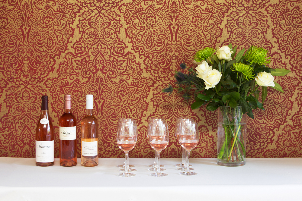 Elegant wine tasting setup with rosé bottles and floral decor. Ideal for social events.