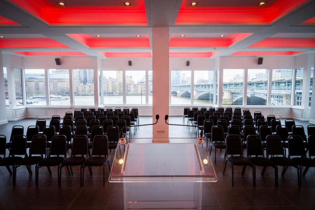 Modern event space in The Mermaid London with black chairs for corporate presentations.