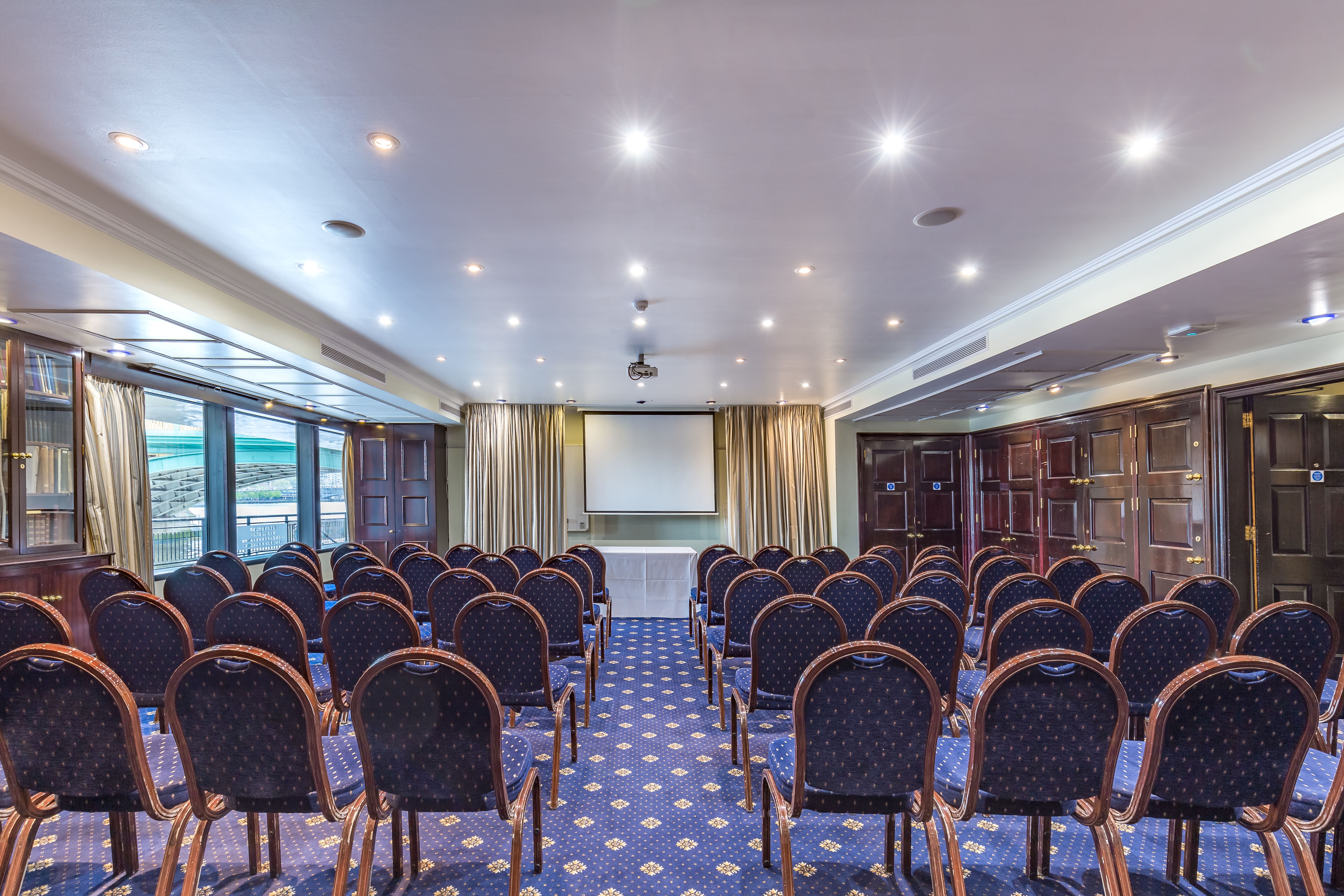 Club Library meeting room with chairs arranged for corporate presentation, modern lighting.