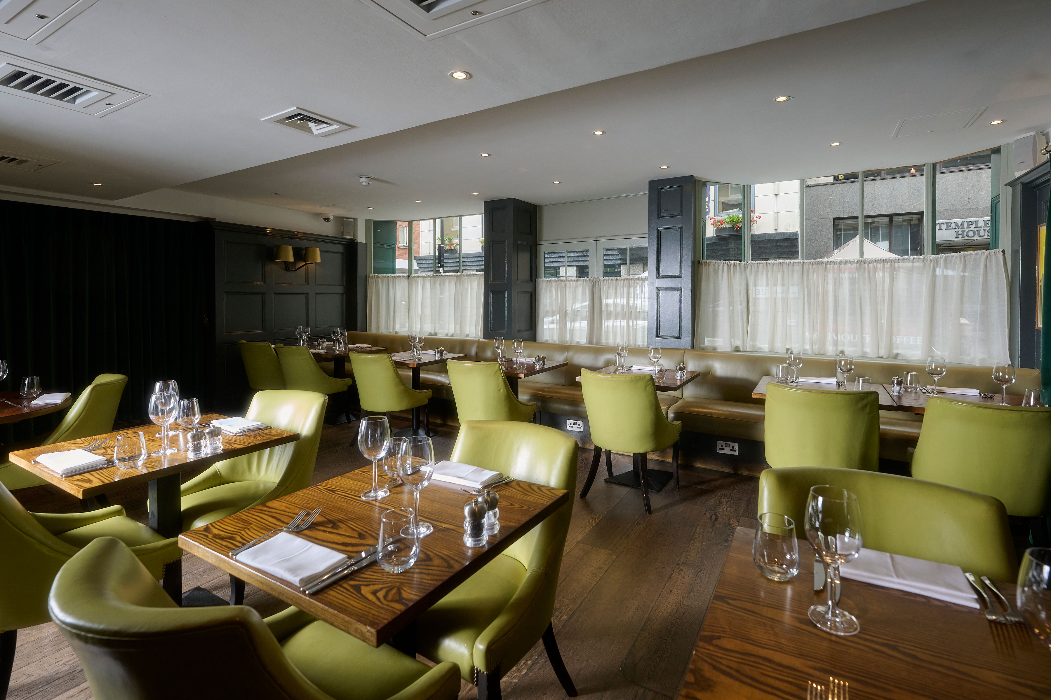 Modern restaurant venue with green chairs, perfect for intimate gatherings and corporate events.
