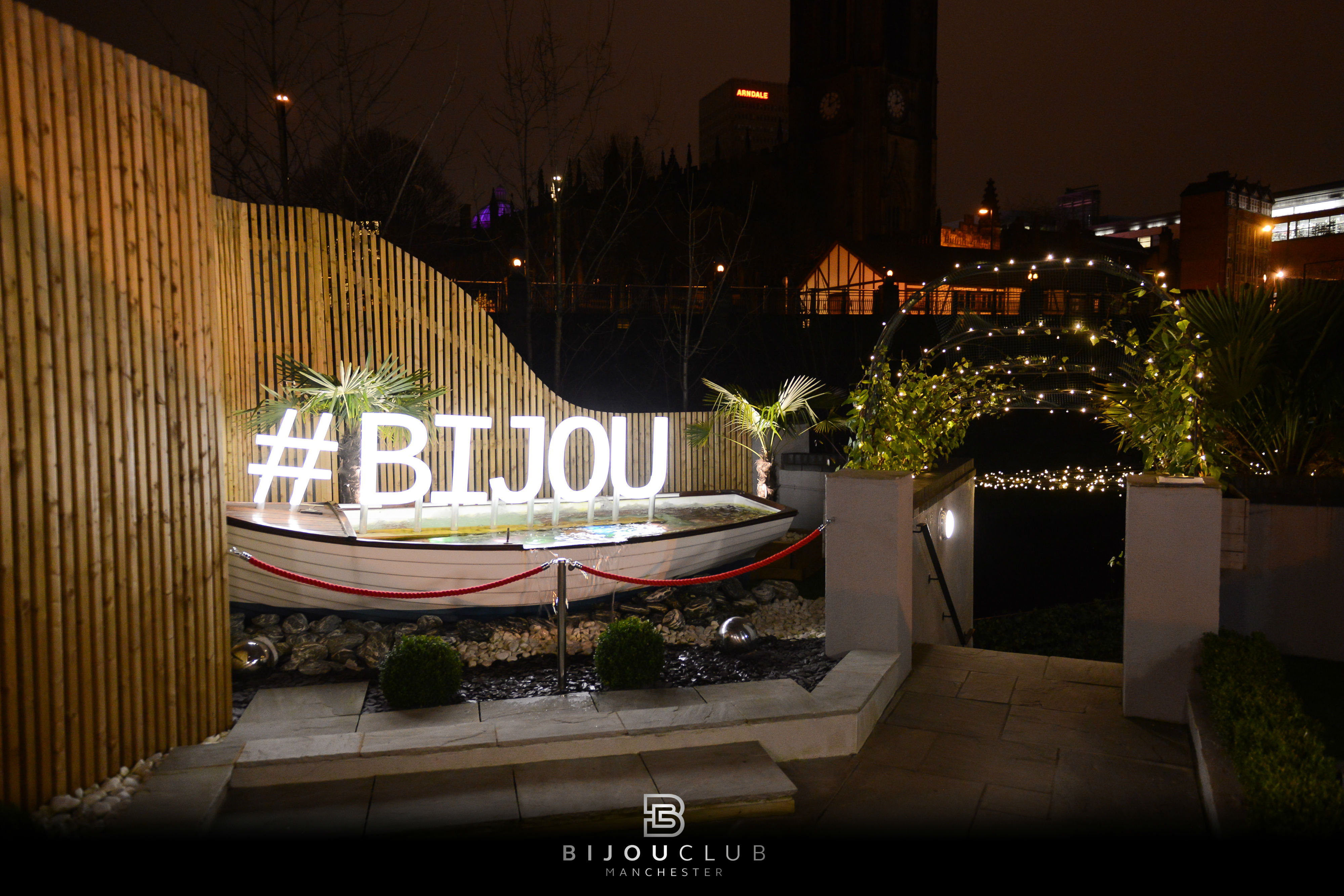 Stylish outdoor event venue at Bijou Club with illuminated branding and lush greenery.