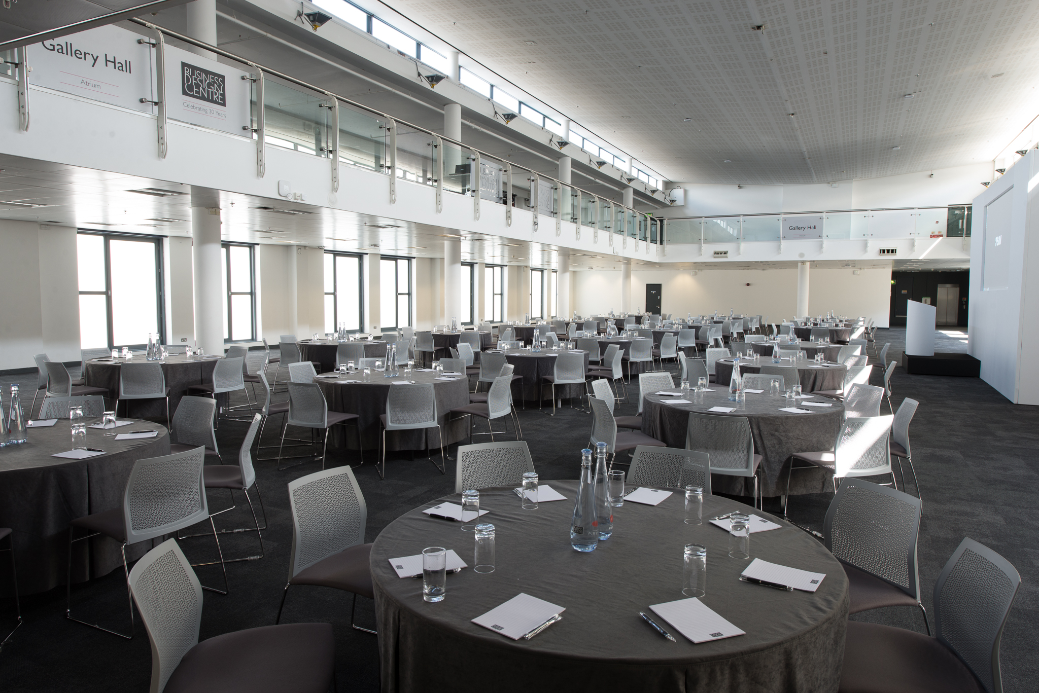 Spacious Business Design Centre atrium with round tables for meetings and banquets.