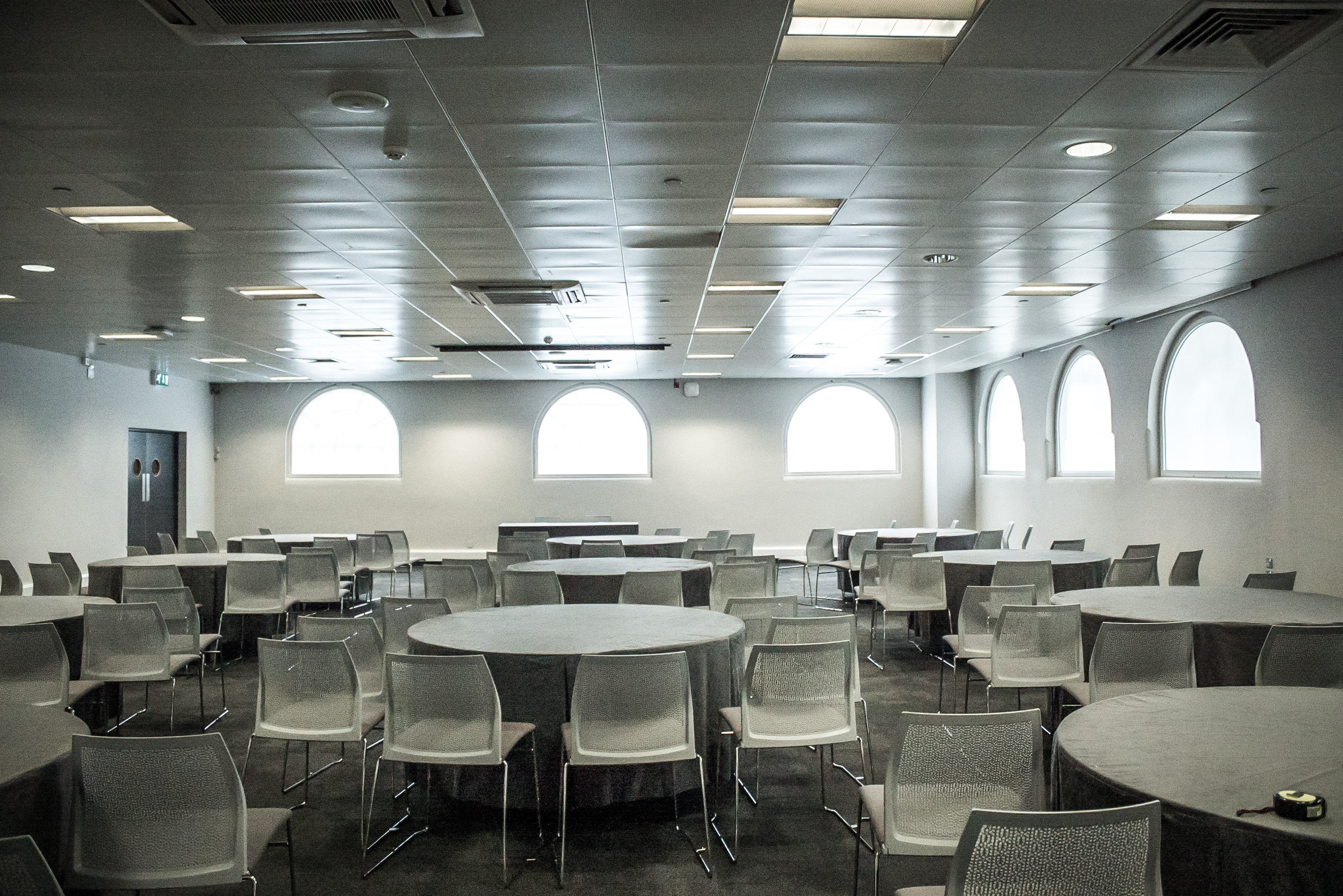 Versatile event space with round tables and natural light for meetings and gatherings.