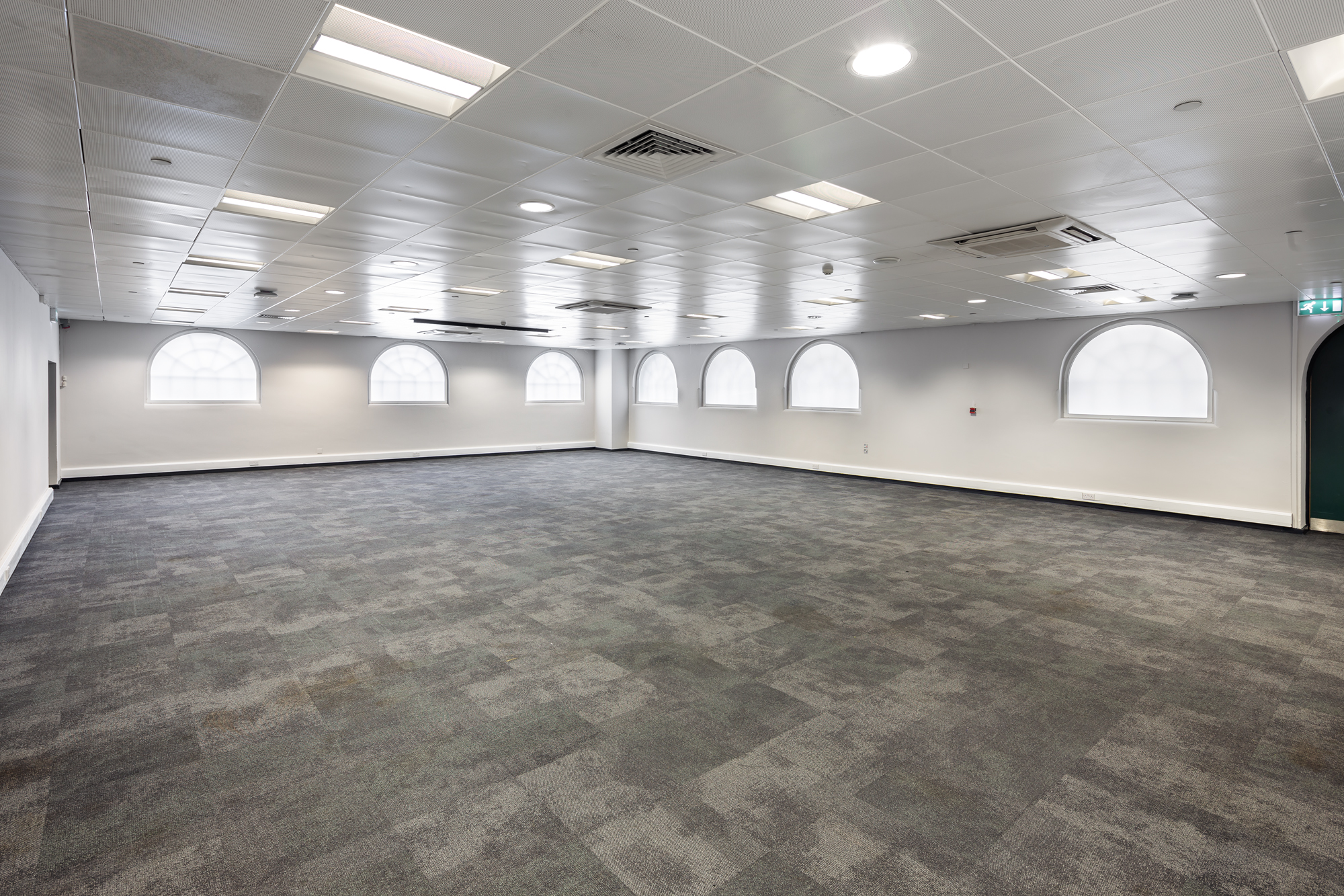 Versatile event space with arched windows, perfect for meetings and workshops.