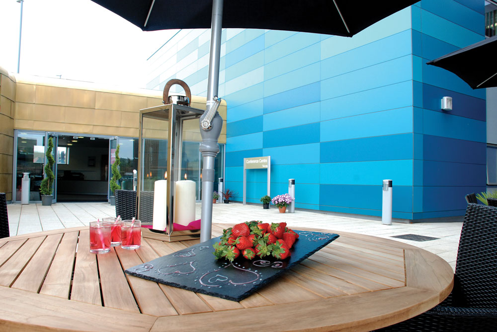 Centenary Suite outdoor event space with wooden table, ideal for summer networking gatherings.