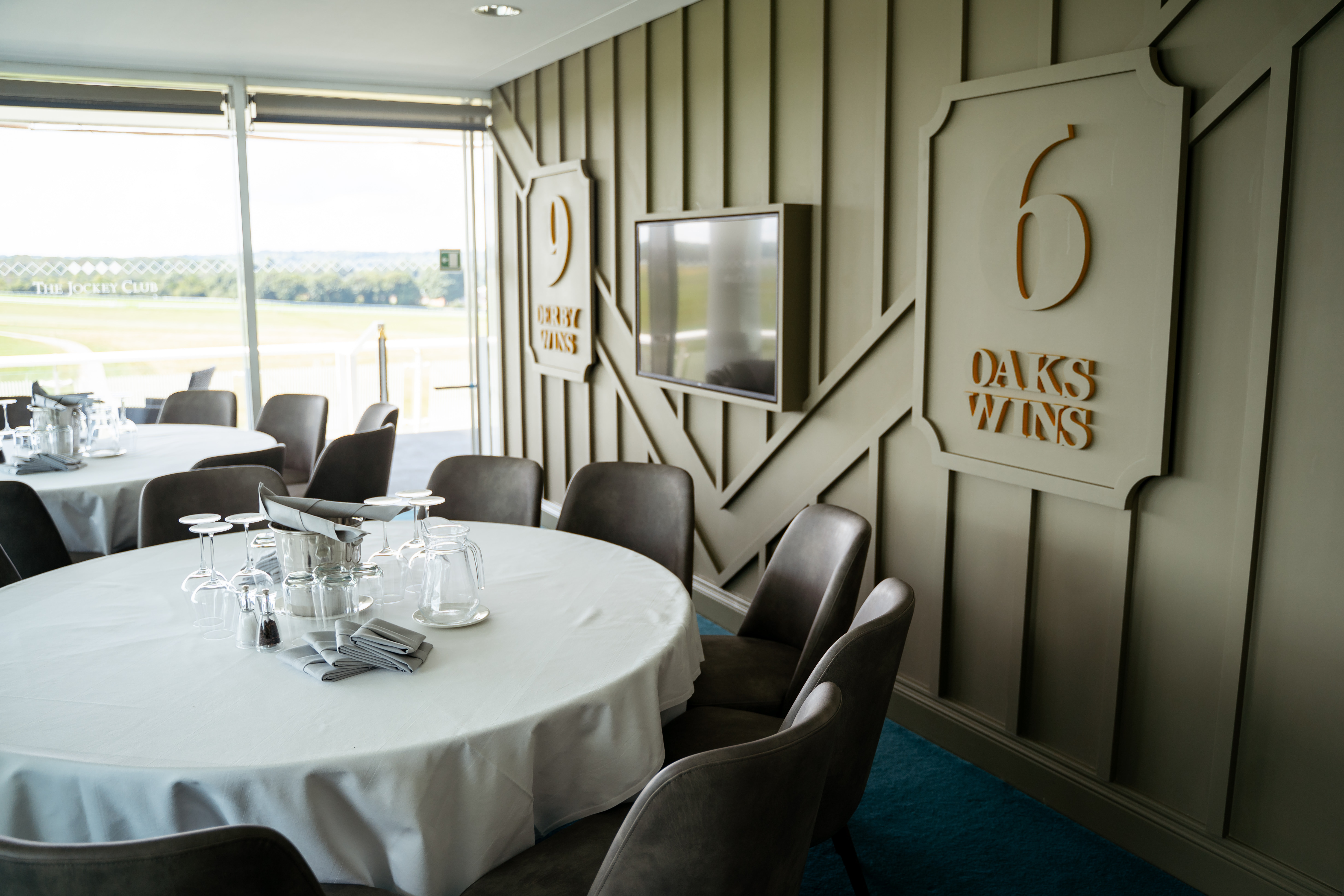 Queen's Double Box at Epsom Downs, elegant corporate event space with round tables.